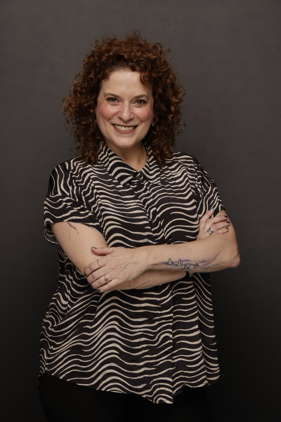 Retrato de Mariana Ruiz, sorrindo, de braços cruzados